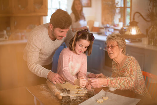 Three generation family cutting shapes in dough to make homemade cookies