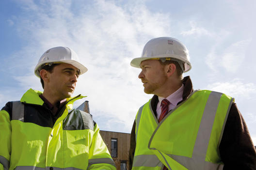 Building contractor and businessman in hard hat and reflective clothing