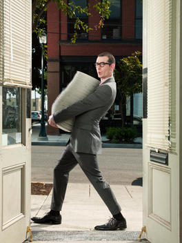 Patrick Miller, Chef de Cuisine at 50 Plates in Portland,walks past a doorway carrying a large stack of plates