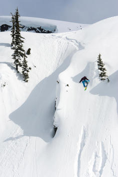 Snowboarder spins off cliff in deep snow