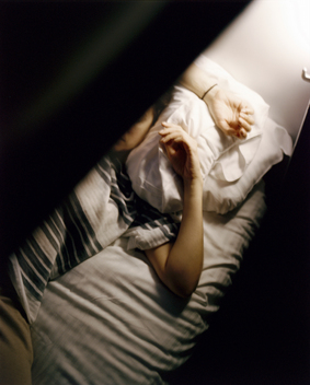 A woman resting on a bed in a bunk on the Caledonian Sleeper train to Scotland