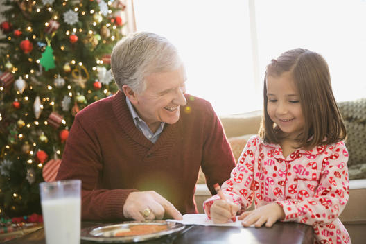 Grandfather helping girl write letter to Santa Claus