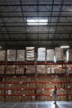 Mixed race woman looking up at boxes in warehouse