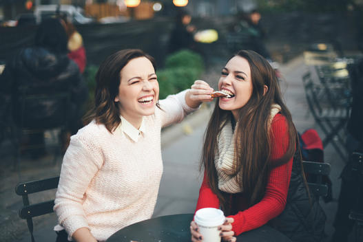 Girl feeding her friend a dessert as they smile