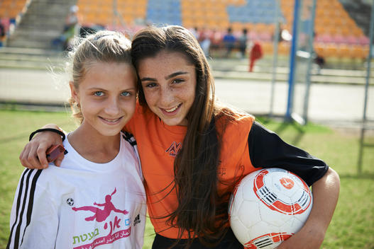 Arab and Israeli girls in soccer uniform hugging