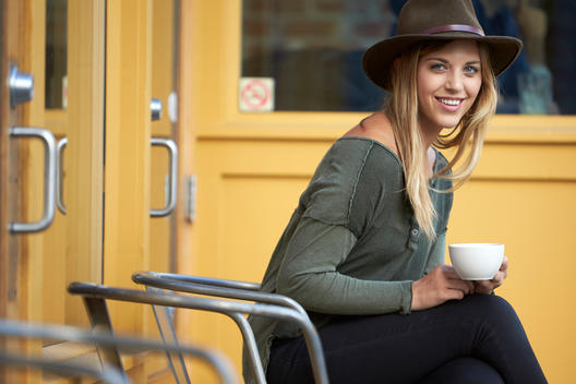 Trendy blonde woman having coffee and smiling.
