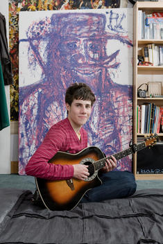 Portrait Of Teenager Playing Guitar In Bedroom