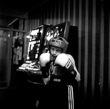 Eleven Year Old From Barnsley Amateur Boxing Club Poses For The Camera, Wearing Head Gear And Holding His Boxing Gloves Up To His Face