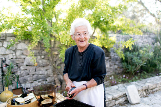White haired Greek Grandma smiling and cooking