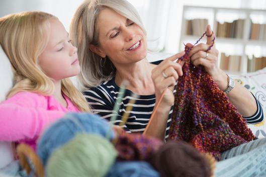 Senior Caucasian woman and granddaughter knitting on sofa