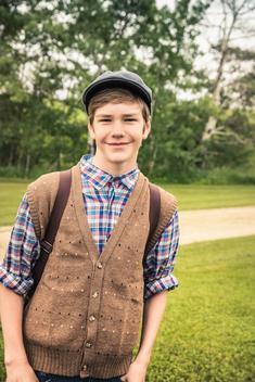Teen boy wearing flat cap carrying backpack looking at camera smiling