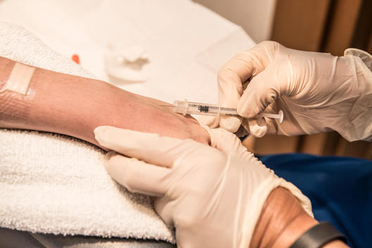 Syringe needle being inserted into a teen girl's arm.