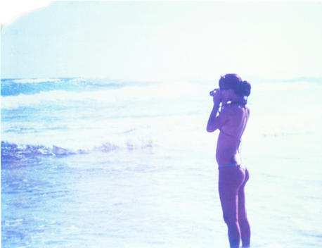 a girl in a swimsuit photographing the ocean