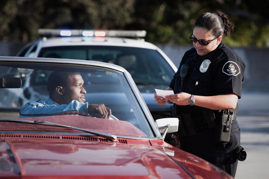 Policewoman checking paperwork of man in convertible