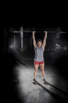 Girl lifting a bar bell at a crossfit gym