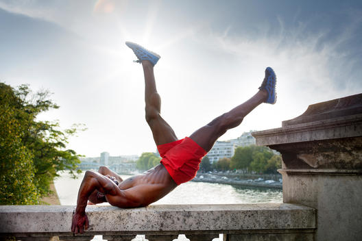 Athletic man exercising on top of marble stone, Seine River in background