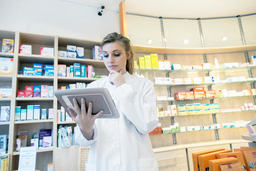 Young pharmacist in pharmacy, using digital tablet