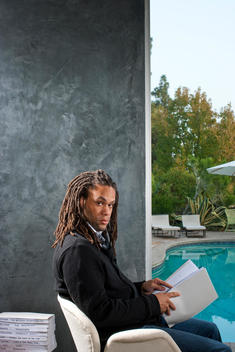 American film executive and founder of the Blacklist Franklin Leonard sits by a pool reading a stack of movie scripts
