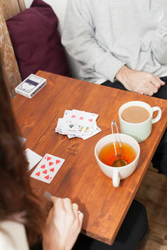 Cropped image of couple playing cards at table in coffee shop