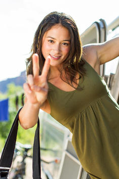 Portrait of woman flashing peace sign to camera