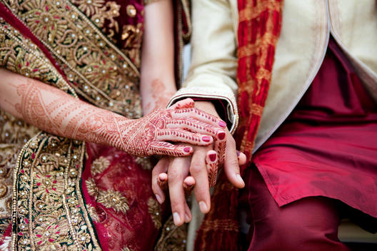 Bride and groom in traditional Indian wedding clothing with henna tattoos