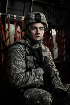 An Air Force Security Forces member sits aboard a military cargo aircraft.