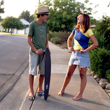 Two Teenagers With Skateboard On Suburban Street