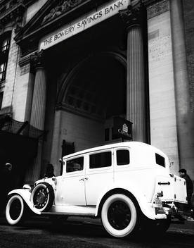 A vintage Rolls-Royce proudly parked in front of a bank building.