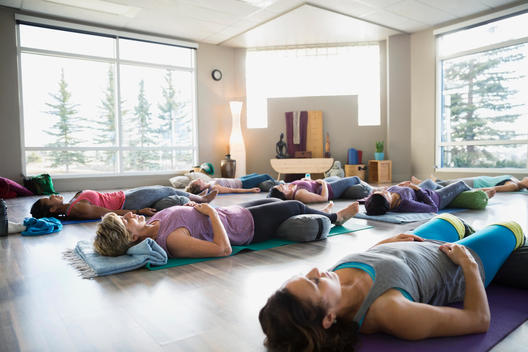 Women laying supported corpse pose in restorative yoga