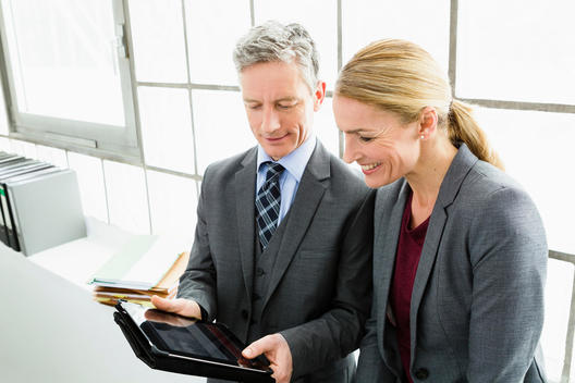 Germany, Businesspeople working on digital tablet, smiling