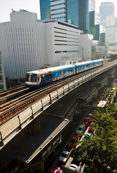 Elevated view of a train line running through an asian city with cars stuck in traffic jam