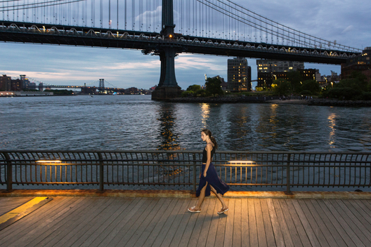 Young woman walking on pier in the evening with the Manhattan Bridge in the background