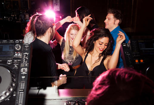 Group of friends dancing in front of DJ in nightclub