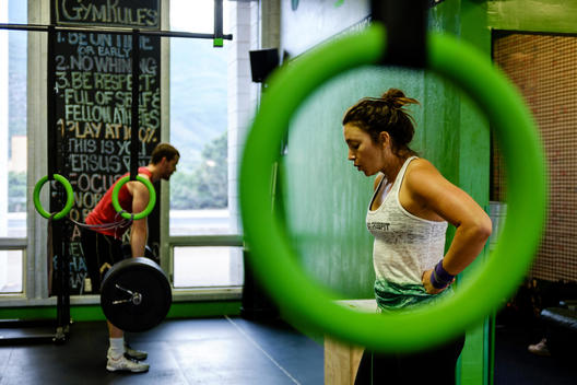 A female Crossfit athlete takes a breather between sets during a workout (WOD) at a Crossfit gym.