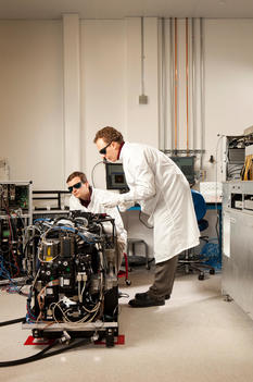 Two scientists examining wires on machinery at Pacific Biosciences, a genome sequencing company referred to as PacBio