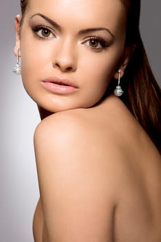 Young Woman With Dark Hair Wearing Pearl Earrings.