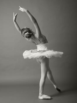 Young ballerina on grey background. Black and white.