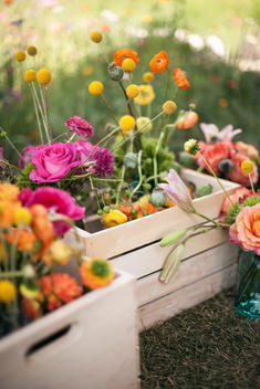 Wedding table decorations. A wooden box of fresh flowers, delicate and brightly coloured blooms. Orange, pink and purple.