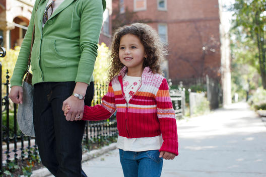 A Mother And Daughter Walk Down A Sidewalk Of A Chicago Neighborhood.