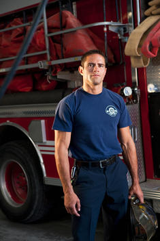 Hispanic fireman standing by fire engine