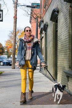 Young woman with shades and dog walking in country town setting