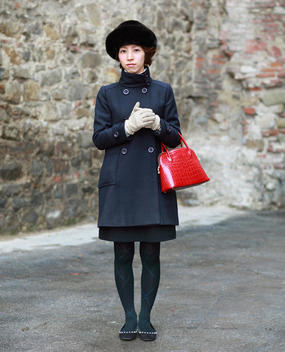 Japanese Woman Wearing A Warm Coat And Hat And Carrying A Red Purse, Florence, Tuscany, Italy.