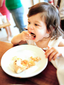 A Young Toddler Eating A Snack At The Table.