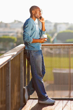 Black man talking on cell phone on balcony