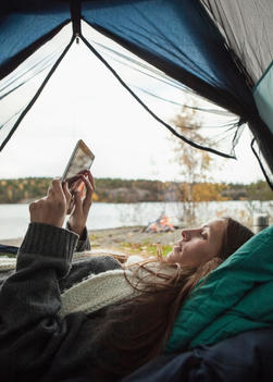 Side view of young woman using digital tablet in tent