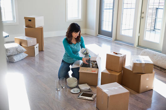 Woman unpacking cardboard boxes in new home