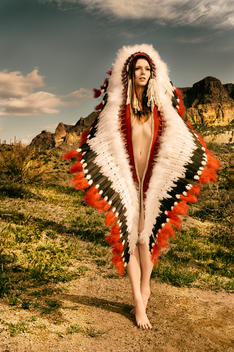 Tall Nude woman in large Native American Headdress in rocky desert | Technicolor Vecchio Moderno