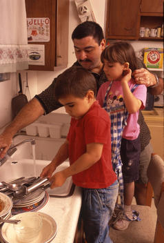 Father washes dishes with his kids