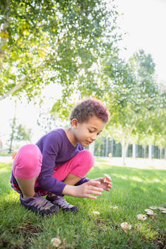 Mixed race girl examining mushrooms outdoors
