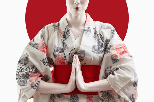 Mixed race woman wearing kimono in front of Japanese flag